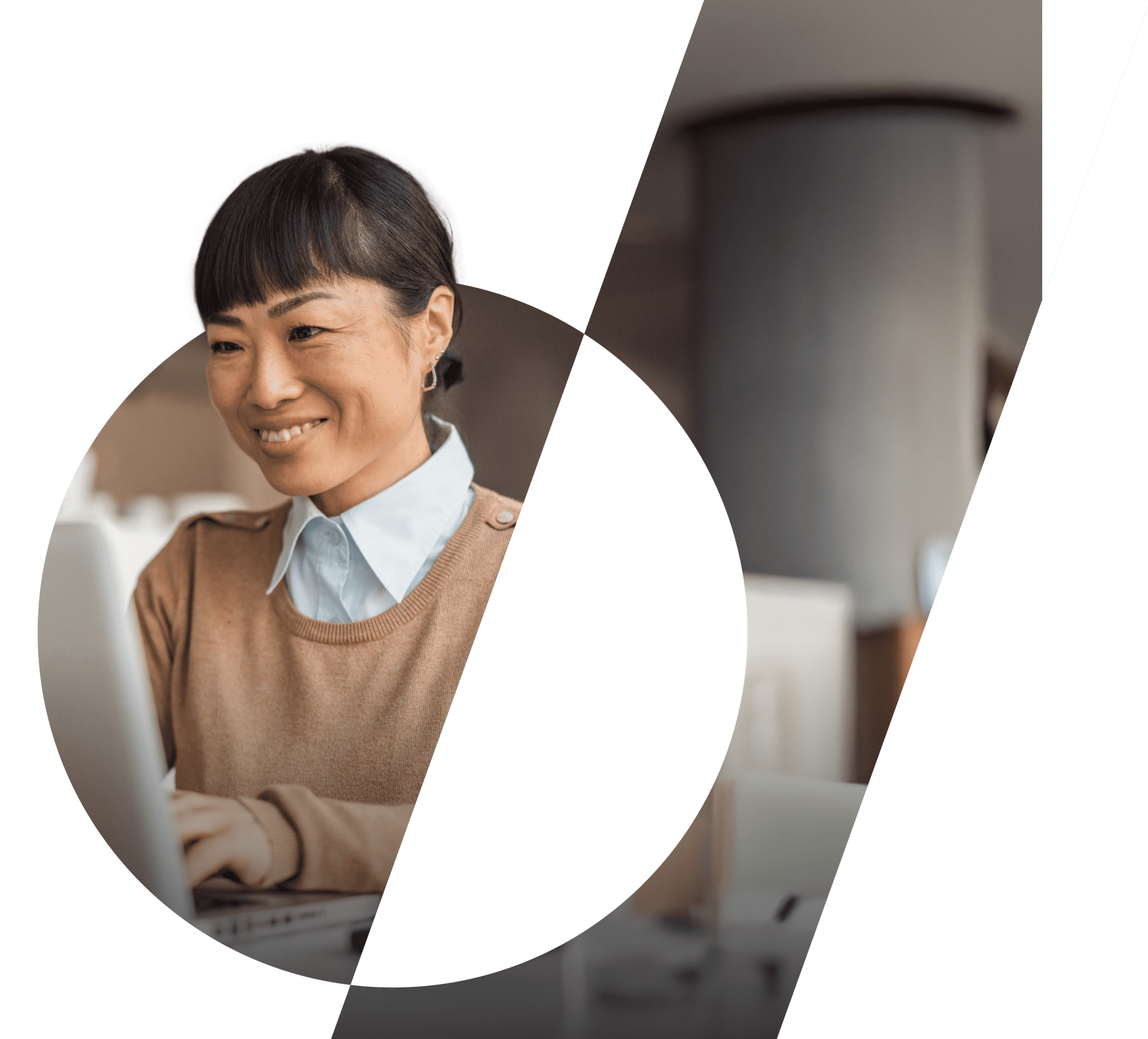 An asian woman smiles whilst working a a computer.