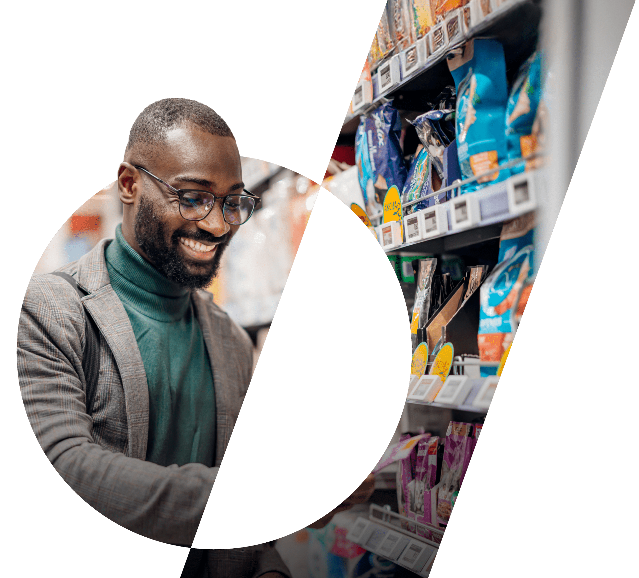 A black man in a jacket, polo neck and glasses smiles whilst looking at objects on a supermarket shelf.