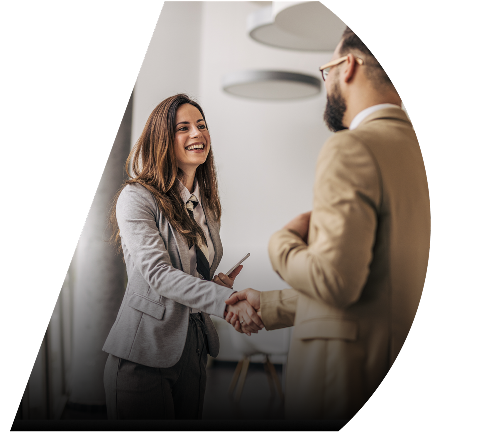 A woman in business attire smiles whilst greeting a man at a marketing event