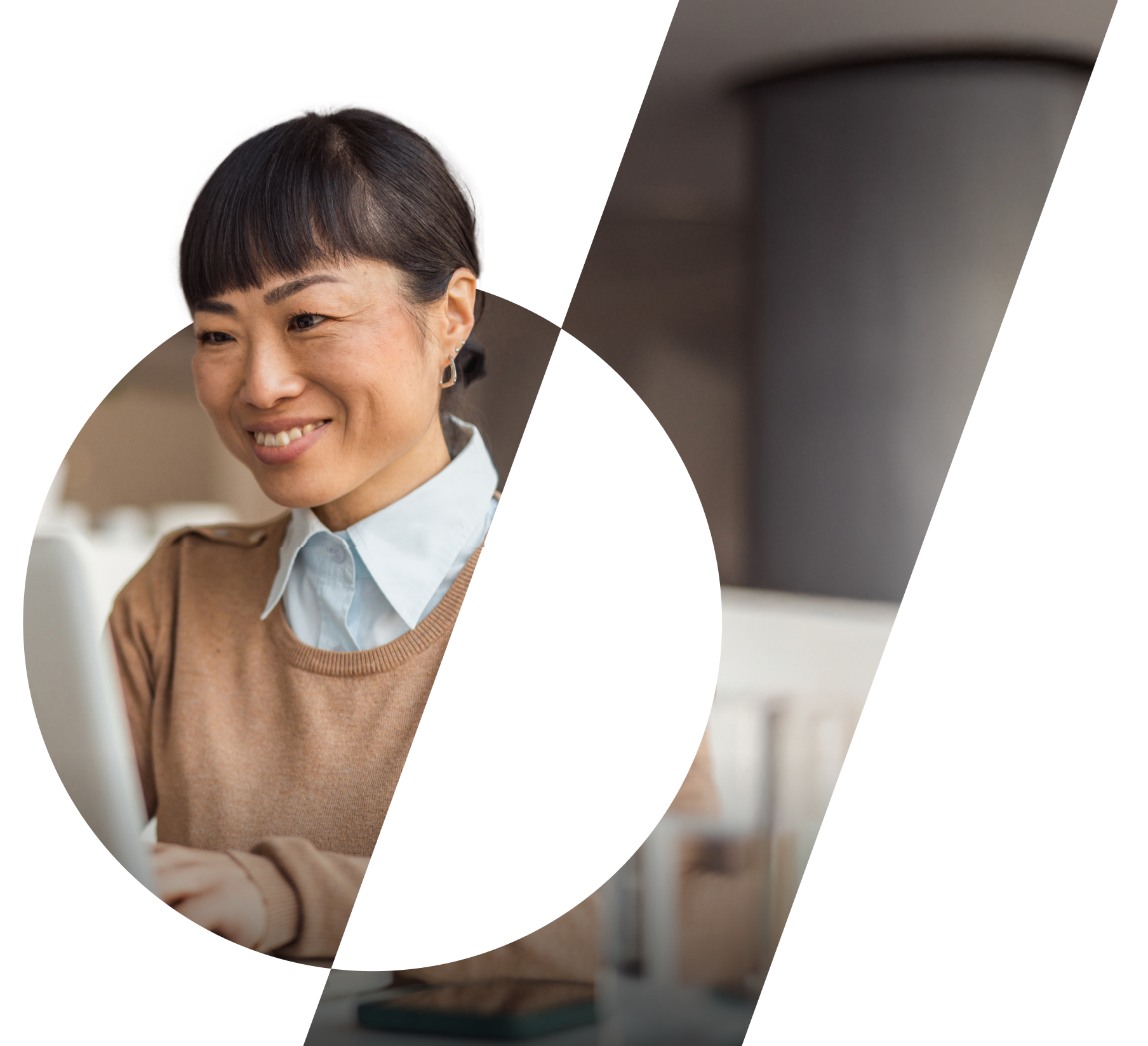 A woman is sat smiling whilst working at a laptop computer