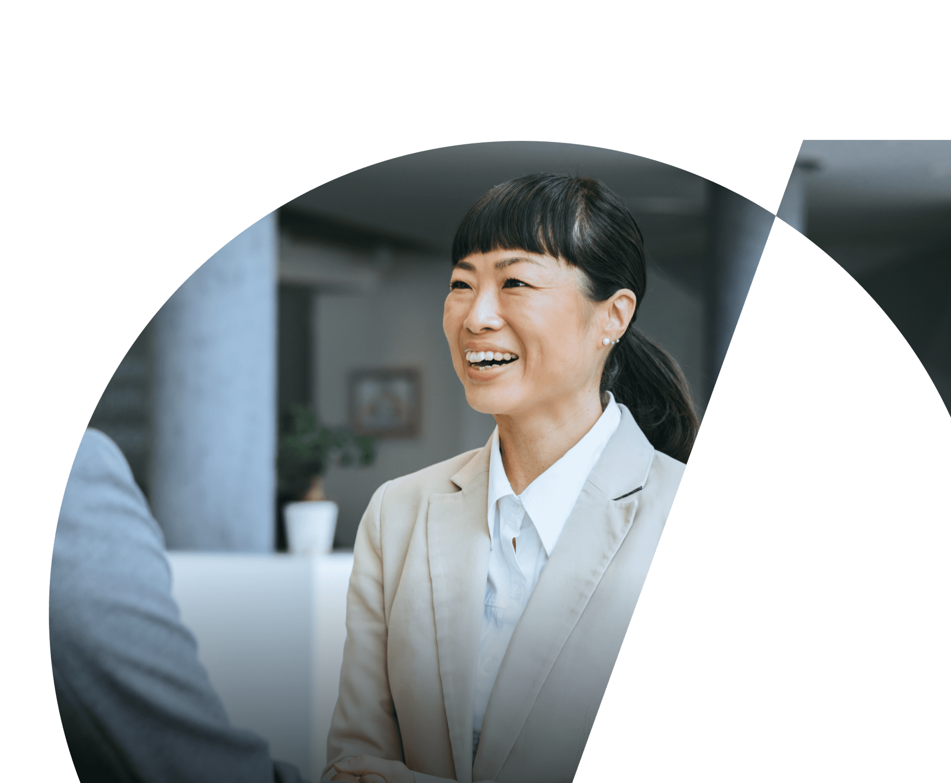 A woman in business attire smiles as she greets someone.